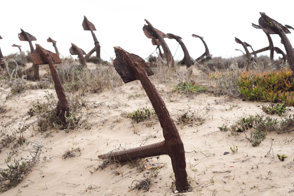 Rusty old anchors on the beach at the Anchor Cemetery graveyard at Praia do Barril beach, in Tavira, Algarve, Portugal