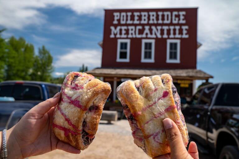 The famous Polebridge Mercantile, a bakery and shop in the small community in Glacier National Park. Hand holds up a famous huckleberry bear claw
