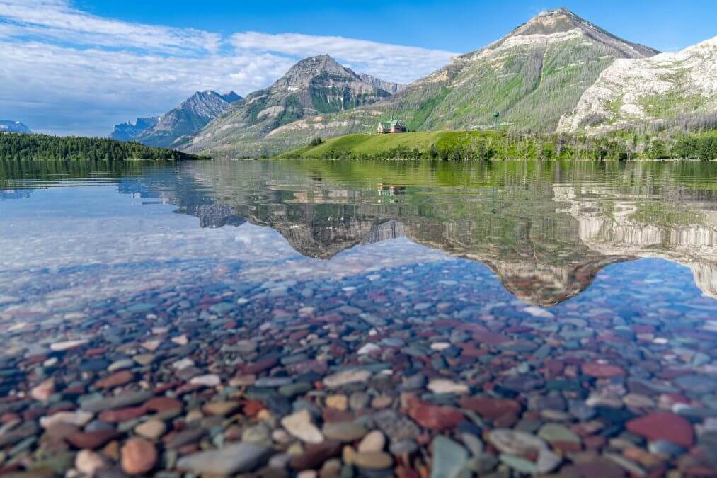 Colorful rocks on Driftwood Beach, with reflection of the Prince of Wales hotel in Waterton Lakes National Park Canada